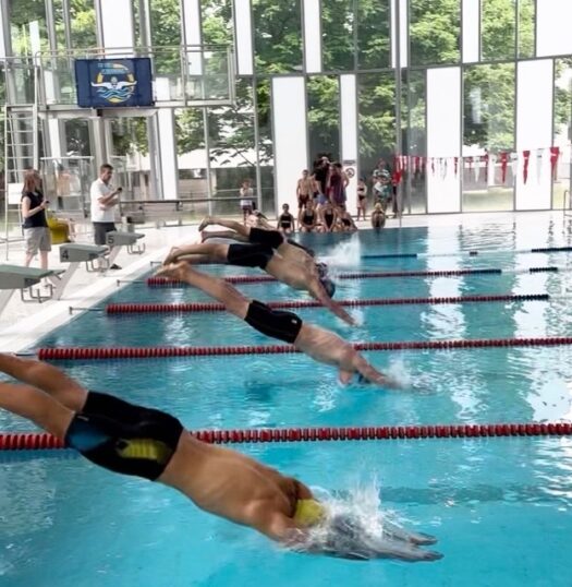 Foto von Schwimmern, die gerade einen Startsprung ins Schwimmbecken machen